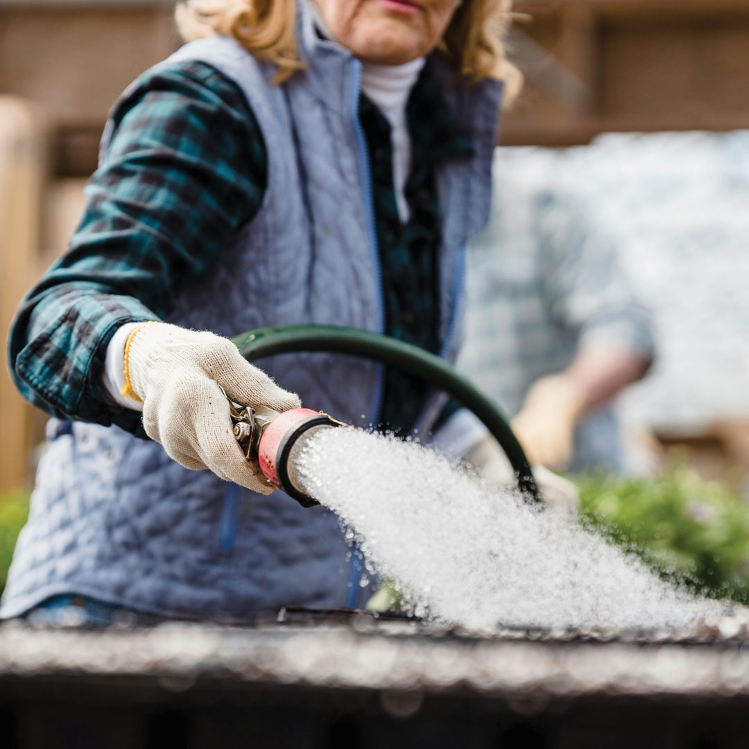 Person in garden center with hose spraying water